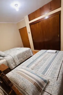 a bedroom with two beds and a wooden cabinet at DEPARTAMENTO Chincha City 1 in Chincha