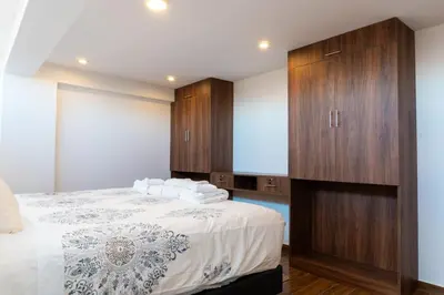 a bedroom with a large bed with wooden cabinets at Lama Vista Living 401 in Cusco