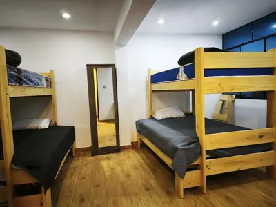 a room with three bunk beds and a mirror at Huaqui House in Ayacucho