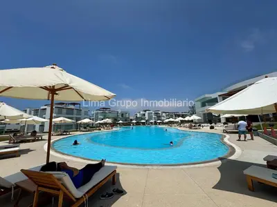 a person laying in a chair next to a swimming pool at Duplex Condominio Míkonos Asia in Asia