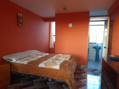a bedroom with a bed with an orange wall at Hospedaje Encanto de Chinchero in Chinchero