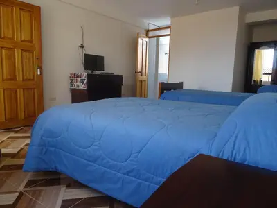 a bedroom with two beds with blue covers on them at Hospedaje Encanto de Chinchero in Chinchero