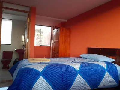 a bedroom with a bed with an orange wall at Hospedaje Encanto de Chinchero in Chinchero