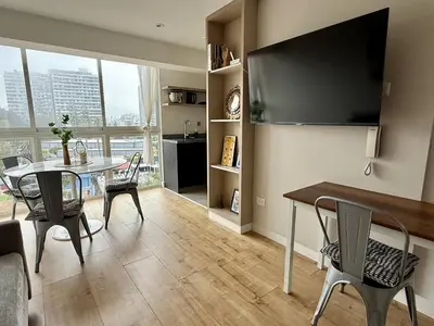 a living room with a table and chairs and a large window at Departamento San Martin in Lima