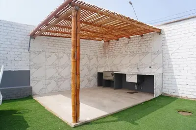 a patio with a wooden pergola on a white brick wall at Apartamento 301 cerca a la playa in Punta Negra