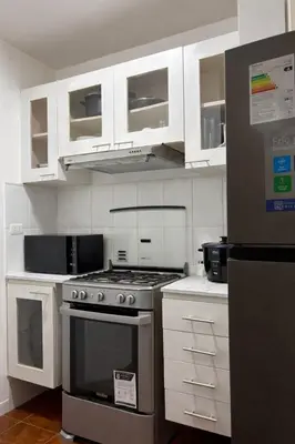 a kitchen with white cabinets and a stove top oven at Acogedor departamento en Malecón Balta con Piscina in Lima