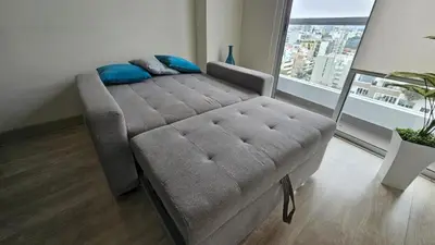a couch in a living room with a large window at PERU STAY Barranco in Lima