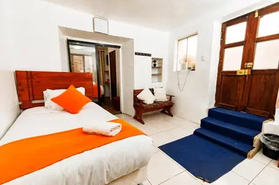 a bedroom with a bed with an orange and blue blanket at Mayu House Inn II a minutos del centro histórico in Cusco