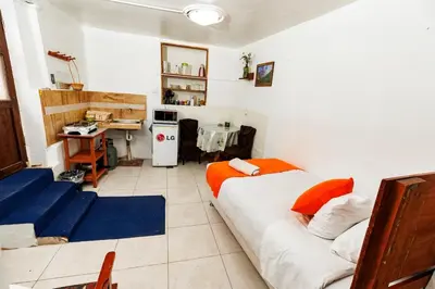 a room with a bed and a desk and a kitchen at Mayu House Inn II a minutos del centro histórico in Cusco