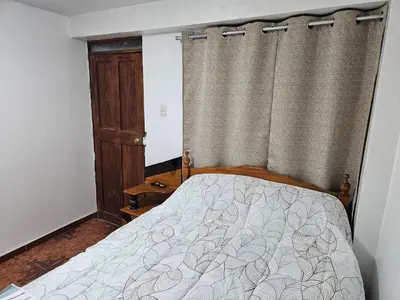 a bedroom with a bed and a window with curtains at Pantaq hostal in Cusco