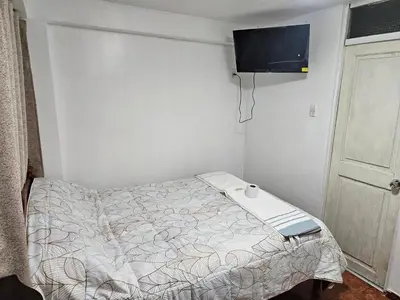 a small bedroom with a bed and a tv on the wall at Pantaq hostal in Cusco