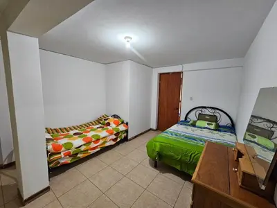 a bedroom with two beds and a desk in it at Munay Ayllu- Tu refugio familiar en Huánuco in Huánuco