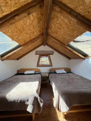 two beds in a room with wooden ceilings and windows at Salkantay House in Anta