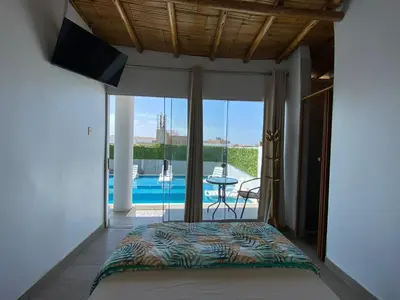a bedroom with a bed and a view of a pool at Casa de Playa - Mara House in Huacho
