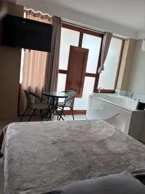 a bedroom with a bed and a table and a tub at Hotel Roma Quillabamba in Quillabamba