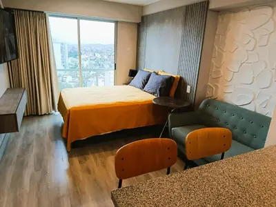 a hotel room with a bed and a chair and a window at JAVIER PRADO ESTE 1501 LOFT- FRENTE a SAN BORJA in Lima