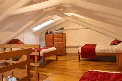 a attic room with two beds and a dresser at Andes Home in Cusco
