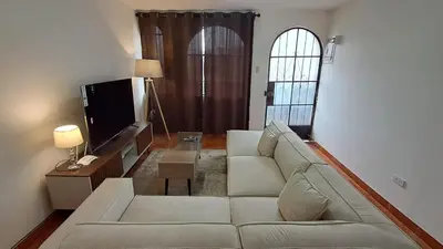 a living room with a white couch and a tv at Modern Apartament Pool & Jacuzzi 1 room in Lima