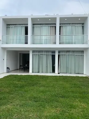 a white building with a lawn in front of it at Prado hotel in Chancay