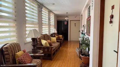 a hallway with couches and chairs in a room with windows at Casa Elena in Cusco