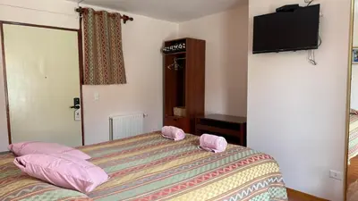 a bedroom with a bed with pink pillows and a television at Casa Elena in Cusco
