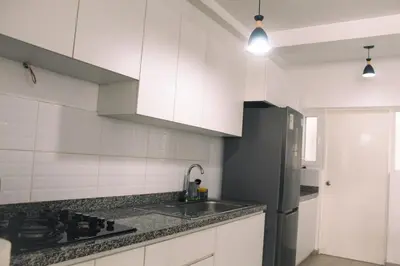 a kitchen with white cabinets and a black refrigerator at Increible casa de playa con vista al lago in San Vicente de Cañete