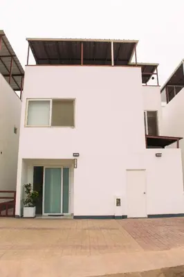 a white building with a door on the side at Increible casa de playa con vista al lago in San Vicente de Cañete