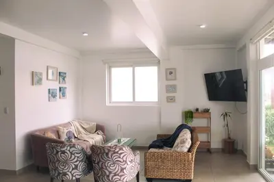 a living room with two chairs and a tv at Increible casa de playa con vista al lago in San Vicente de Cañete
