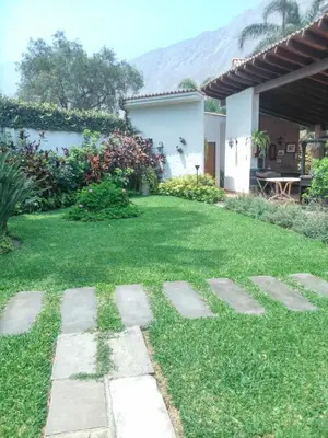 a garden with grass and stones in front of a house at Nice country house with a swimming pool and large garden in Cieneguilla