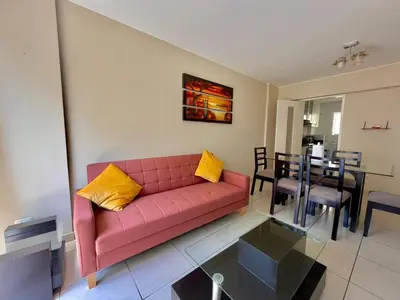 a living room with a pink couch and a dining room at Casa de Liz in Lima