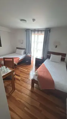 a room with two beds and a table with a tableasteryasteryasteryasteryastery at Xima Cusco Kenamari in Cusco