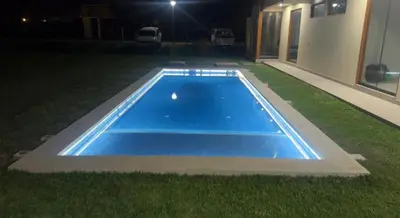 a blue swimming pool in the grass at night at House 3M in Condominium Fundo Pradera, Chocaya - Lima - Perú in Asia