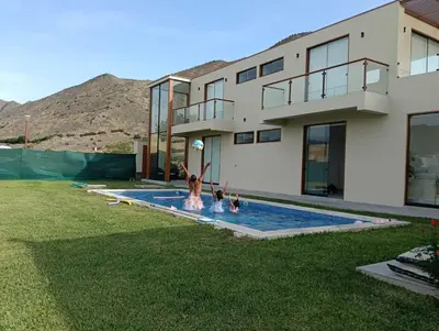 two children playing in a swimming pool in front of a house at House 3M in Condominium Fundo Pradera, Chocaya - Lima - Perú in Asia