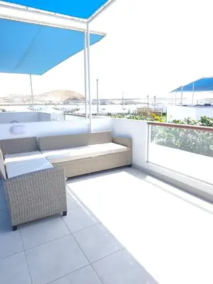 a balcony with chairs and an umbrella on a building at Vacaciones sin Estres, ambiente relajado y familiar in San Antonio