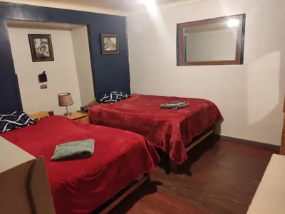 a room with two beds with red sheets and a mirror at Victoria home in Cusco