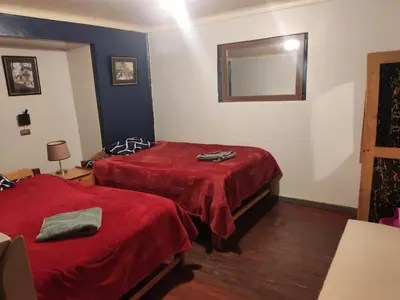a room with two beds with red sheets and a mirror at Victoria home in Cusco