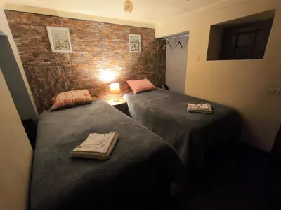 two beds in a room with a brick wall at Victoria home in Cusco