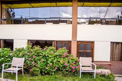 two chairs sitting in front of a bush with flowers at Departamentos Santa Ana Barrio Tradicional in Cusco