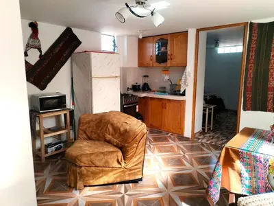 a living room with a chair and a kitchen at Encanto del Cusco in Cusco
