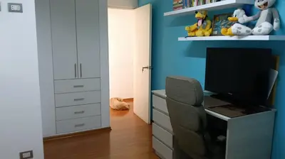 a bedroom with a blue wall and a chair and a television at Habitación in Lima