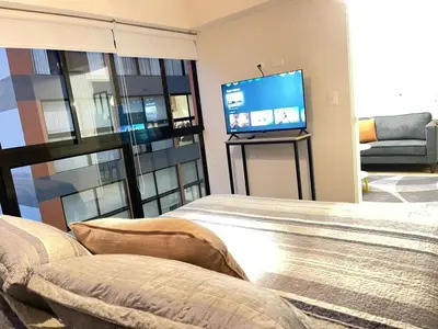 a living room with a bed and a flat screen tv at M24 Departamento de 2 Dorm 2 baños - Frente Embajada de USA in Lima