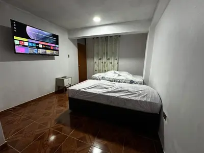 a bedroom with a bed and a tv on the wall at Quinta Maravillas in Ayacucho