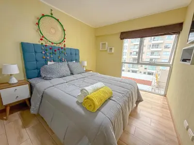 a bedroom with a bed with a blue headboard and a window at Amplio depa 3 habitaciones en Costanera in Lima