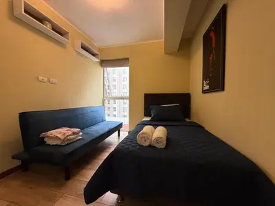 a bedroom with a blue bed and a couch at Amplio depa 3 habitaciones en Costanera in Lima