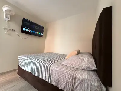 a bedroom with a bed with a tv on the wall at Departamento Cerca al Aeropuerto Jorge Chavez in Lima