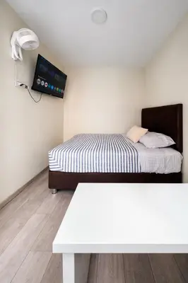 a small bedroom with a bed and a table at Departamento Cerca al Aeropuerto Jorge Chavez in Lima
