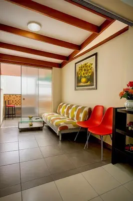 a living room with a couch and red chairs at A cozy apartment in the heart of Miraflores in Lima