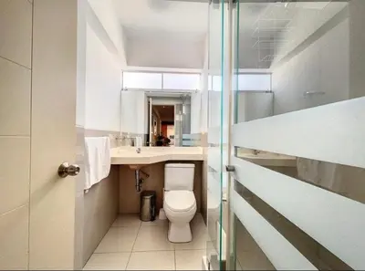 a white bathroom with a toilet and a sink at A cozy apartment in the heart of Miraflores in Lima