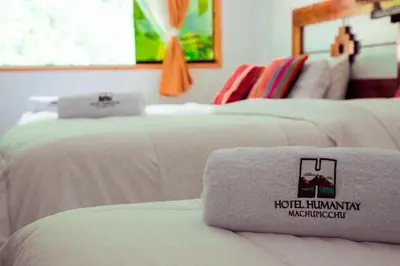 two beds in a hotel room with a towel on the bed at Hotel MachuPicchu Humantay in Machu Picchu
