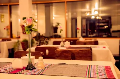 a table with a vase with a pink rose on it at Hotel MachuPicchu Humantay in Machu Picchu
